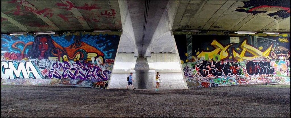 Walkers stroll past colourful murals on the south side of the bridge.