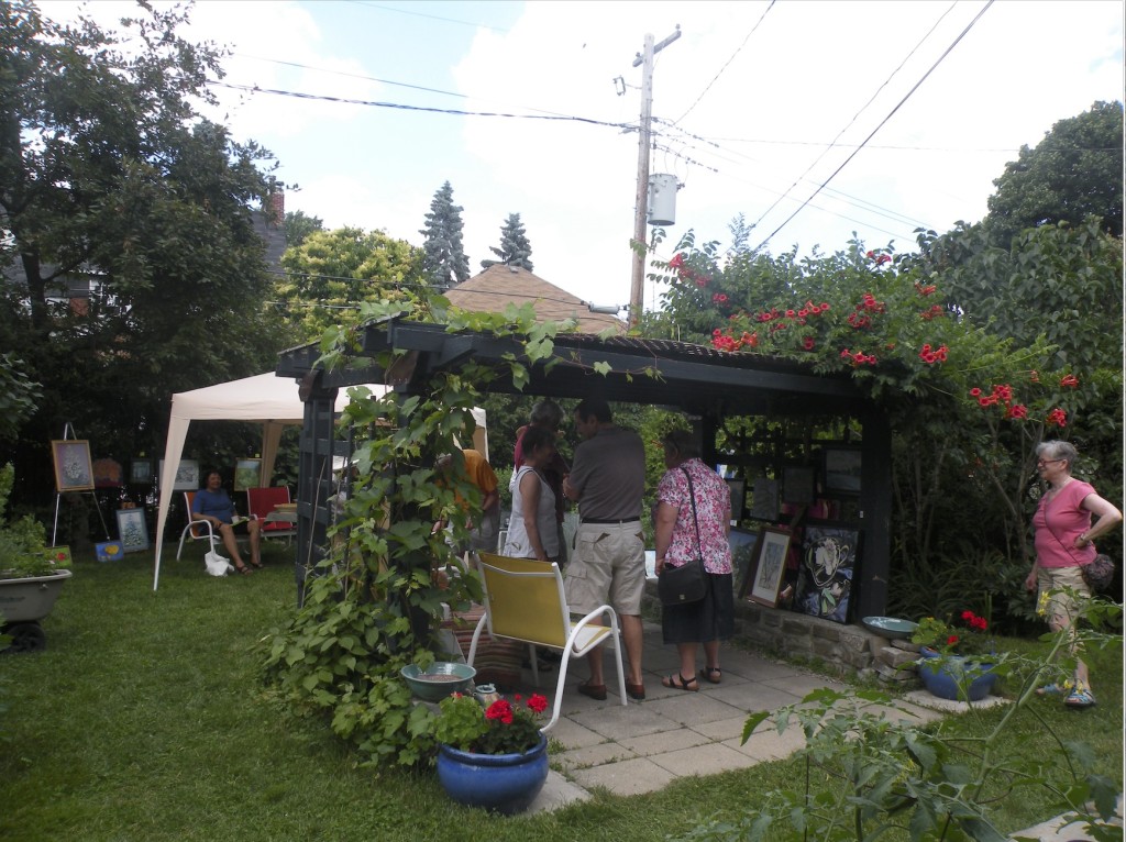Art lovers gathered under an arbour of fiery trumpet flowers to view works by artist Maureen O'Neill. PHOTO: Julie Houle Cezer